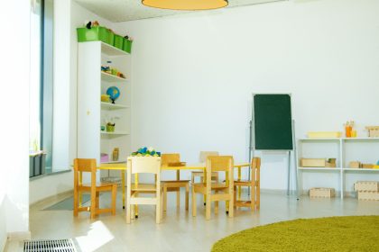 Sala colorida de educação infantil com mesas, cadeiras e materiais pedagógicos.