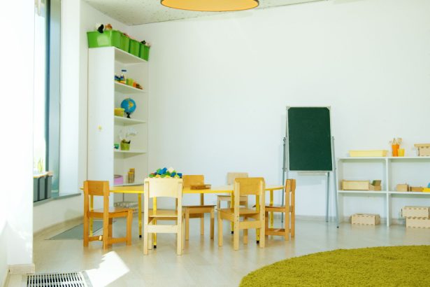 Sala colorida de educação infantil com mesas, cadeiras e materiais pedagógicos.