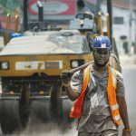 Trabalhador com equipamento de segurança atua em uma obra de pavimentação de rua.
