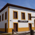Fachada de um prédio público histórico de arquitetura clássica, sob céu azul.