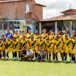 Equipe de futebol amador posa reunida no campo antes de uma partida.