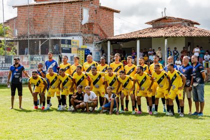 Equipe de futebol amador posa reunida no campo antes de uma partida.
