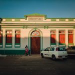 Prédio histórico de uma prefeitura brasileira, com fachada colorida e pessoas circulando ao entardecer.