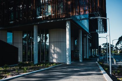 Fachada de uma unidade de saúde contemporânea, com área ajardinada e caminho de acesso.
