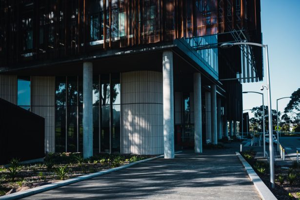 Fachada de uma unidade de saúde contemporânea, com área ajardinada e caminho de acesso.