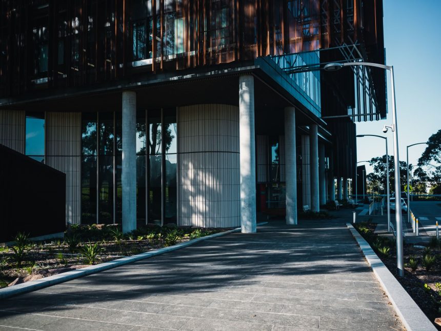 Fachada de uma unidade de saúde contemporânea, com área ajardinada e caminho de acesso.