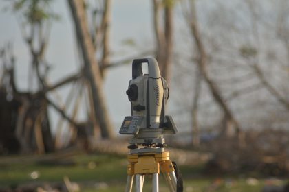 Equipamento de estação total utilizado para levantamento topográfico em uma área externa.